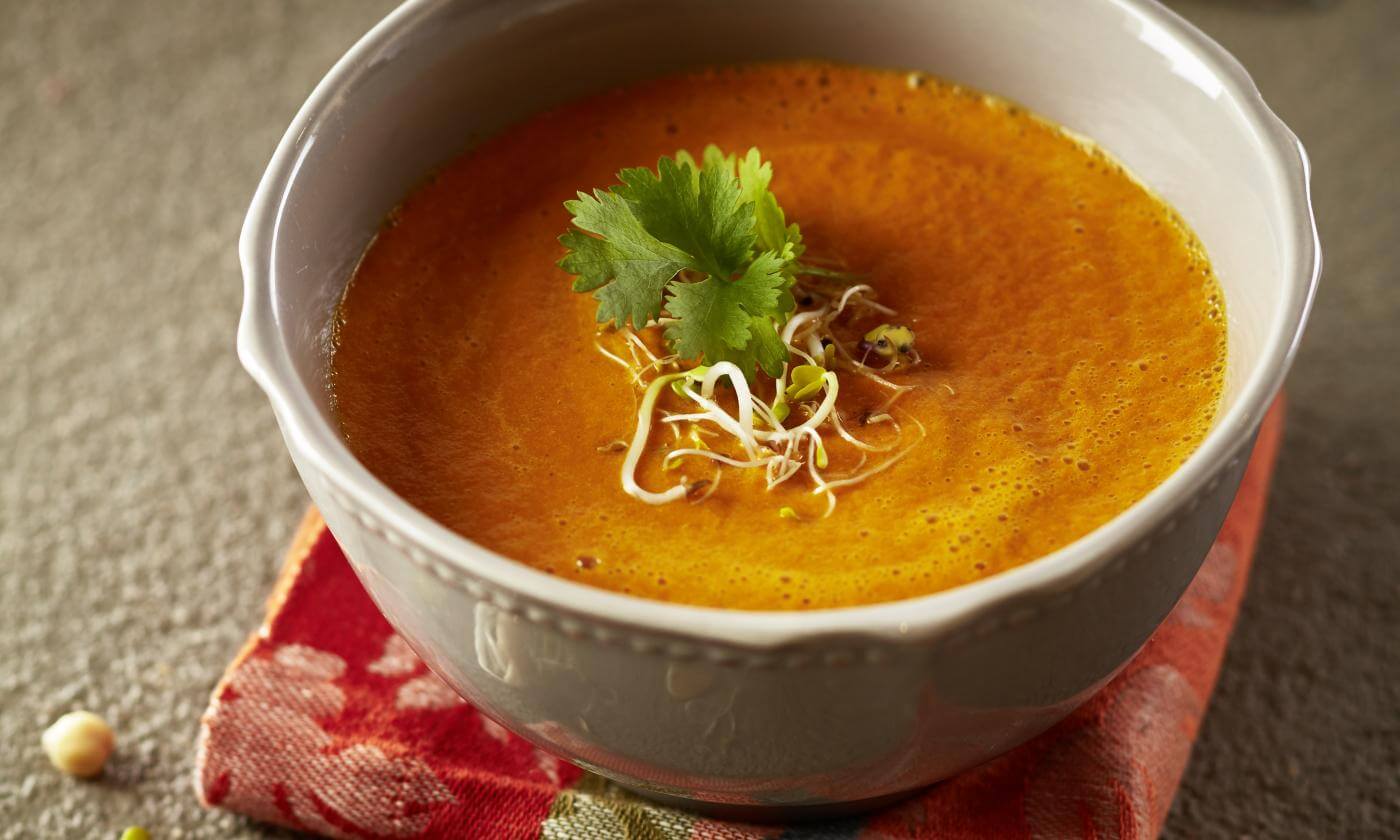 Paprika-Kokos-Chia-Suppe mit Ingwer, Korianderblatt und Sprossen als Dekoration